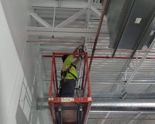 Worker On Lift Installing Alarm Wiring